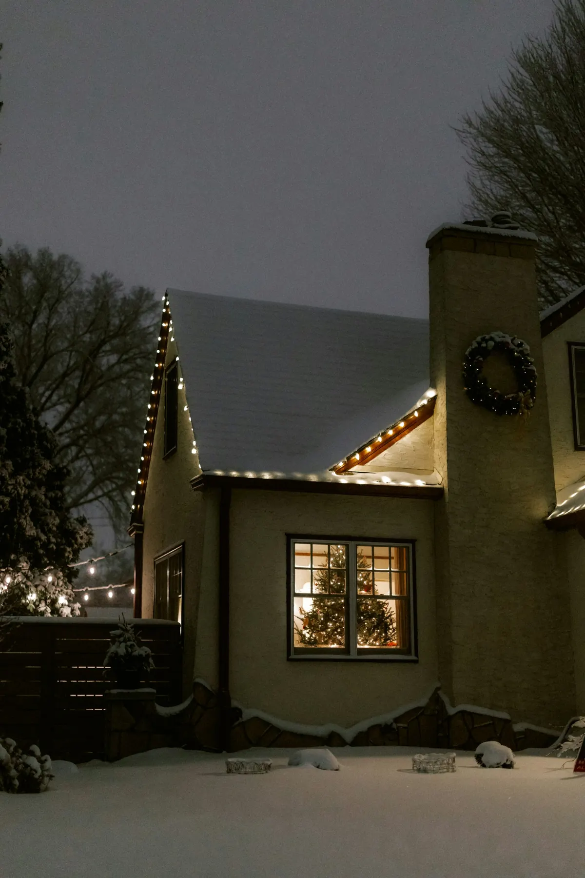Snow-covered roofline with C9 bulbs still clipped along the gutter edge