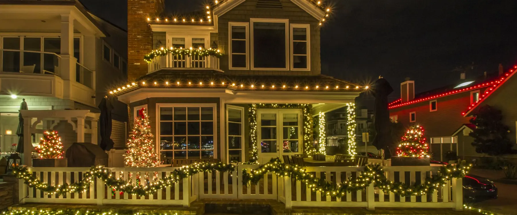 Two-story home with gables and dormers traced in warm white lights